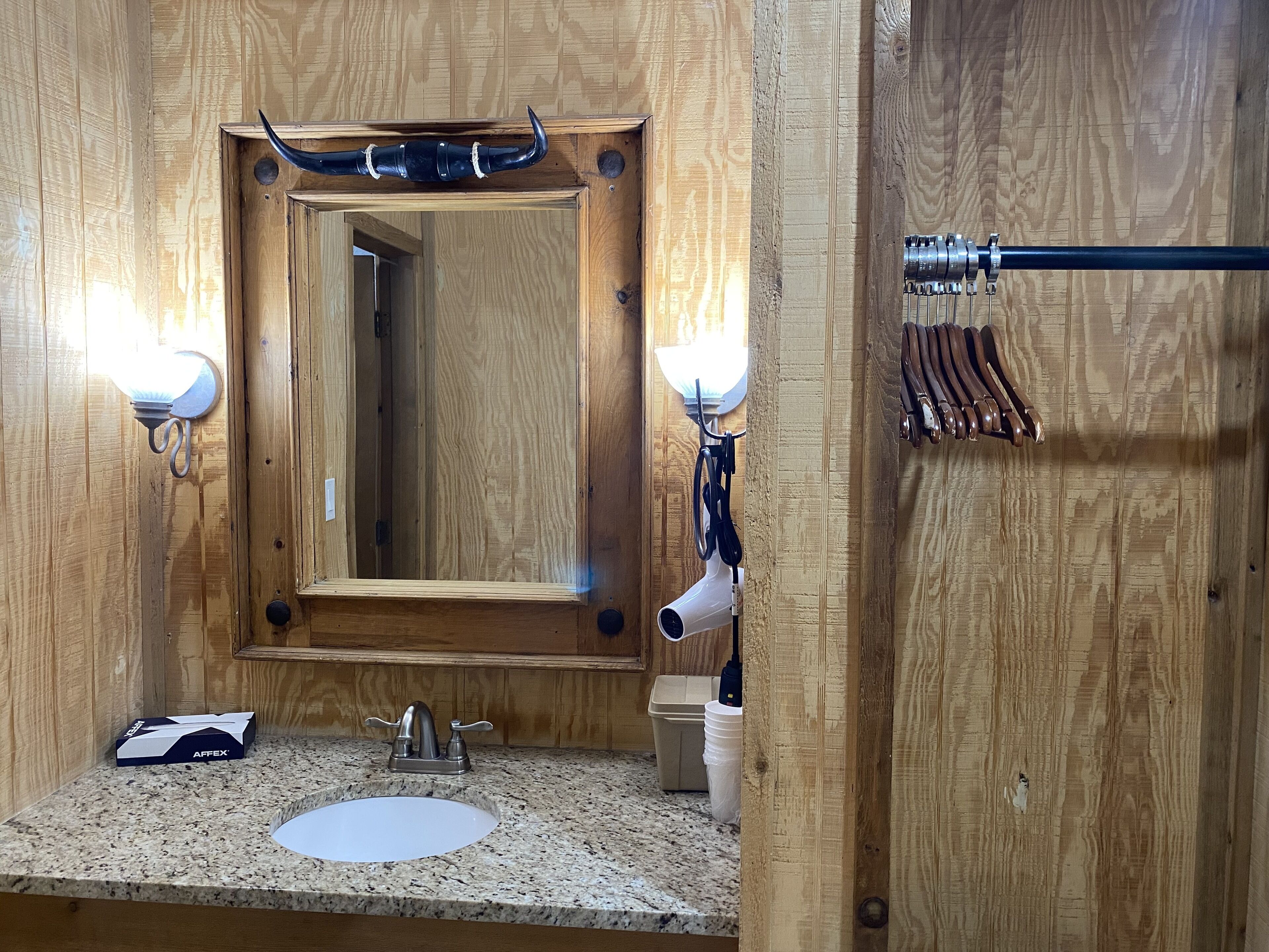A wooden bathroom with a sink, mirror, and towel rack.
