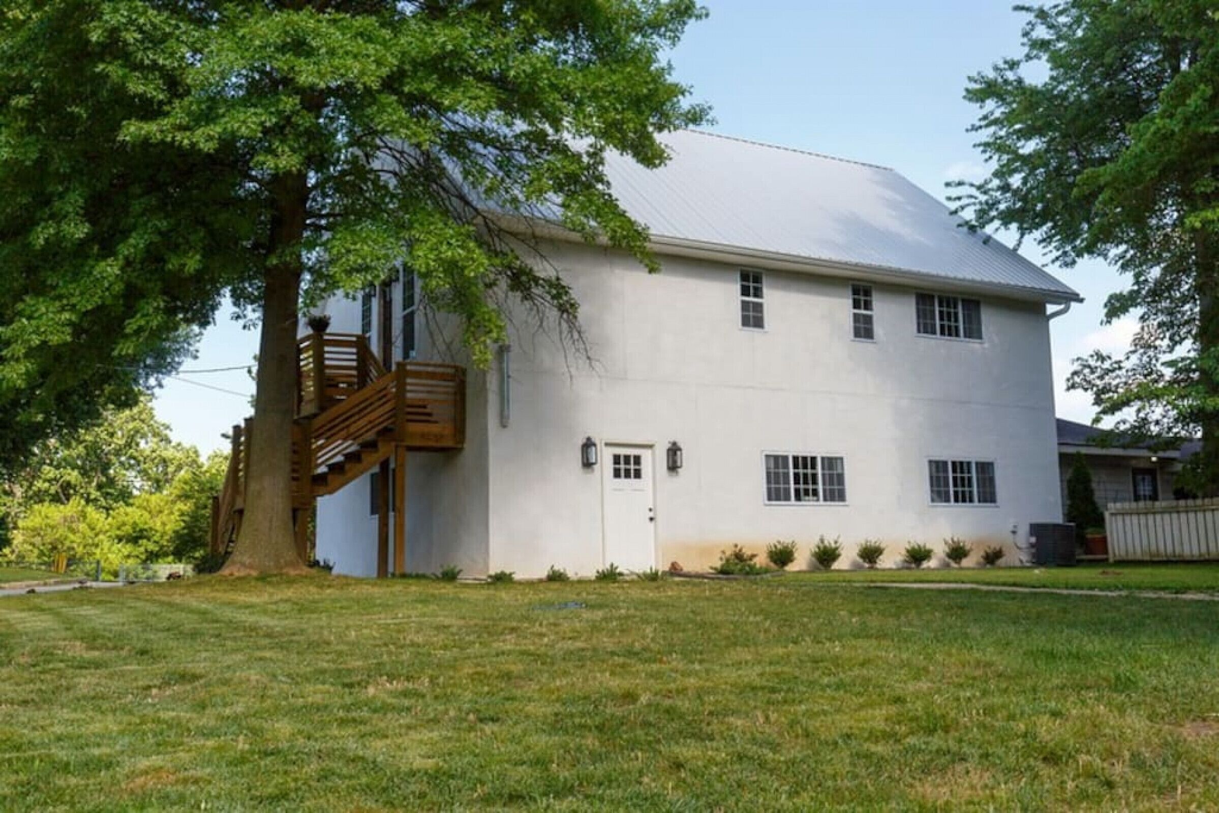 A two-story building with a white exterior, a wooden staircase, and a small porch.