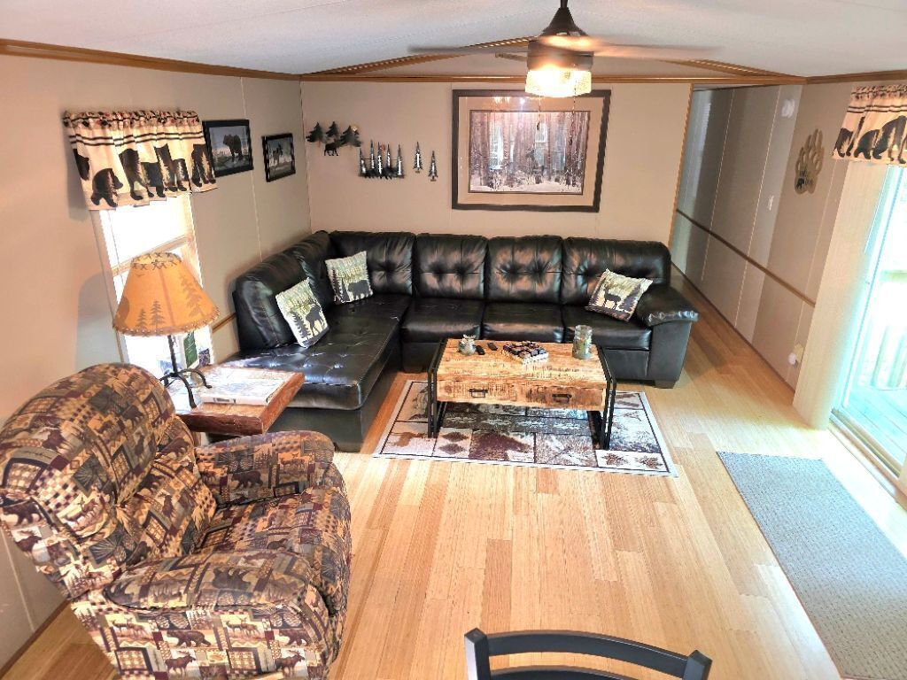 Un salon avec un canapé en cuir noir, un fauteuil à motifs et une table basse en bois.