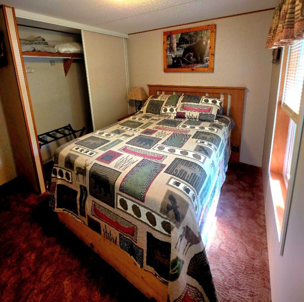 Een slaapkamer met een bed, een kledingkast en een schilderij aan de muur.