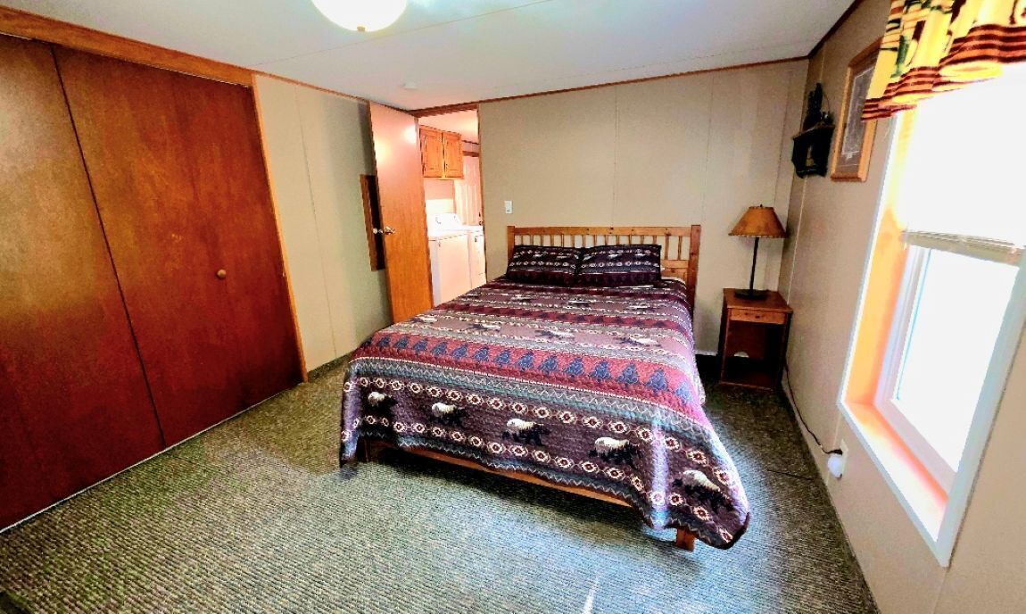 A bedroom with a bed, a nightstand, a lamp, and a window.