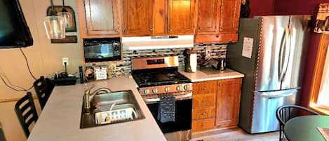 A kitchen with wooden cabinets, a stove, microwave, and refrigerator.
