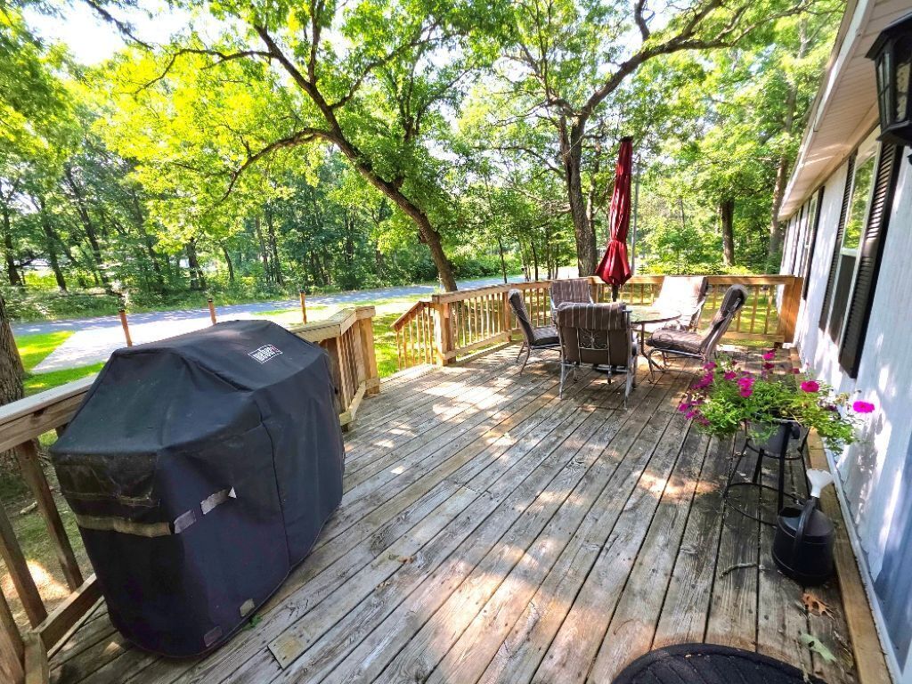 A wooden deck with outdoor furniture, a grill, and potted plants.