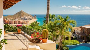 Ein Balkon mit Blick auf einen Strand, einen Berg und ein Schwimmbad.
