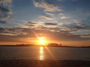 A sunset over a calm body of water with a distant shoreline.