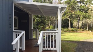 A wooden deck with white railings leading to a dark blue building with the number 28209. - Our Cozy Getaway  (Ocean Park)