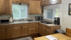 A kitchen with wooden cabinets, a microwave, toaster, sink, and a coffee maker. - Our Cozy Getaway  (Ocean Park)