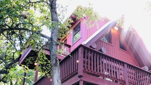 Une cabane rustique avec des fondations en pierre, des balcons en bois et une véranda.