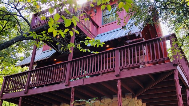 Un bâtiment rustique en pierre, doté d’un balcon en bois rouge et d’un escalier en pierre menant à l’entrée.