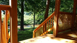 A wooden deck with a staircase leading to a grassy area surrounded by trees. - Private Catch & Release Lake - Boat Rental Included! Close To Lake Cumberland! (Russell Springs)