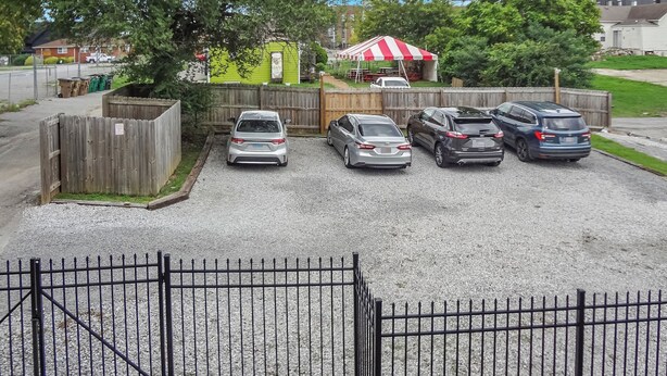 A parking area with multiple cars, a wooden fence, and a red and white striped canopy. - 2 BR 8 min to Downtown - Free Parking -C (Nashville)