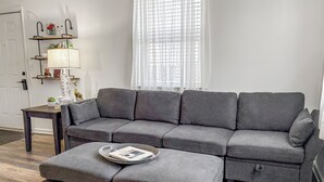 A grey sectional sofa with storage drawers, a small side table, and a magazine tray. - 2 BR 8 min to Downtown - Free Parking -C (Nashville)