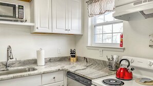 A kitchen with white cabinets, a stainless steel sink, a microwave, a red kettle, and a window with a view of the outside. - 2 BR 8 min to Downtown - Free Parking -C (Nashville)