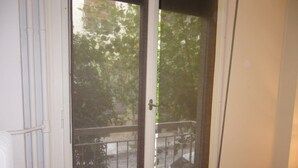 Ein Zimmer mit einer Schiebetür aus Glas, die auf einen Balkon mit Metallgeländer führt.