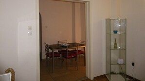 Ein Essbereich mit Tisch und Stühlen, eine Glastruhe mit einer Vase und eine Tür zu einem anderen Raum.