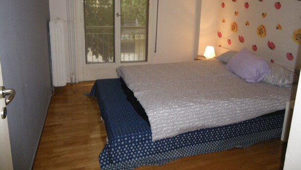 Ein Schlafzimmer mit einem Bett, einem Fenster und einer blumengedeckten Wand.