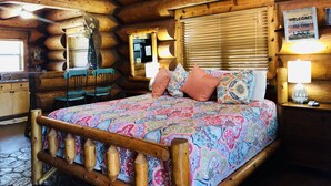 A log cabin bedroom with a wooden bed, a desk, and a chair. - Waterfront Cabin w/ Stunning Lake Views & Porch (Burnet)