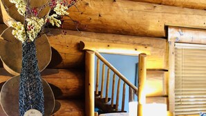 A wooden interior with a dining table, chairs, a vase with flowers, and a staircase. - Waterfront Cabin w/ Stunning Lake Views & Porch (Burnet)