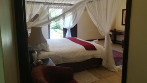 A bedroom with a bed, a nightstand, a chair, and a desk. - The Moon and Sixpence Garden Guest House (Muldersdrift)