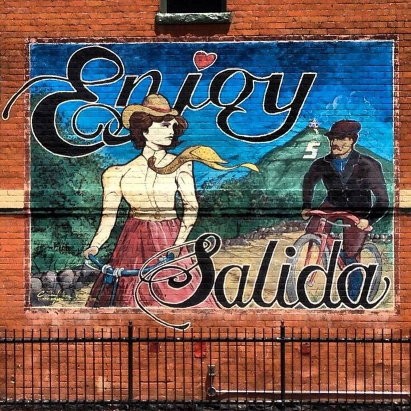 A mural with the text 'Enjoy Salida' and a person riding a bicycle.
