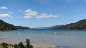 A coastal view with boats on calm waters, surrounded by hills. - Tirimoana House (Anakiwa)