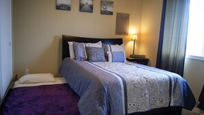 A bedroom with a bed, a nightstand, and a lamp.