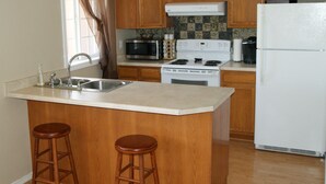 A kitchen with wooden cabinets, a microwave, stove, and a refrigerator.