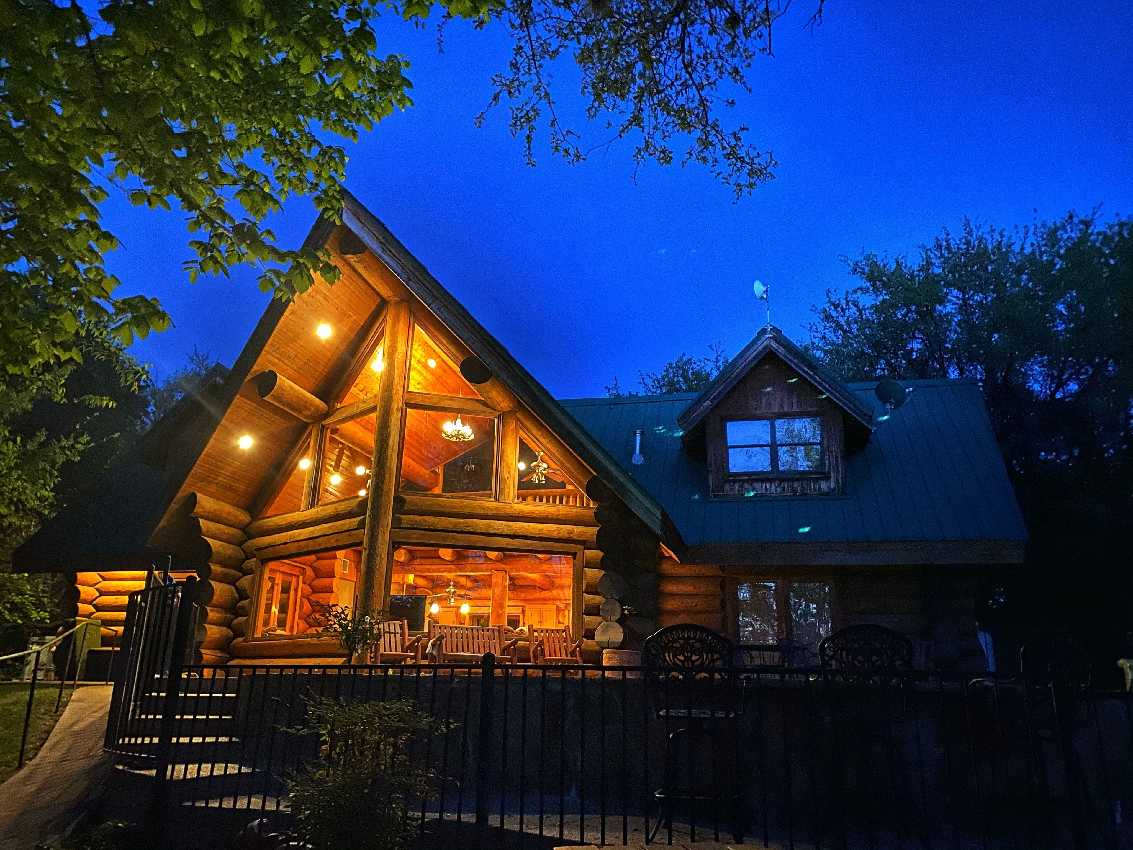 A log cabin with a large front porch, multiple windows, and a chimney.