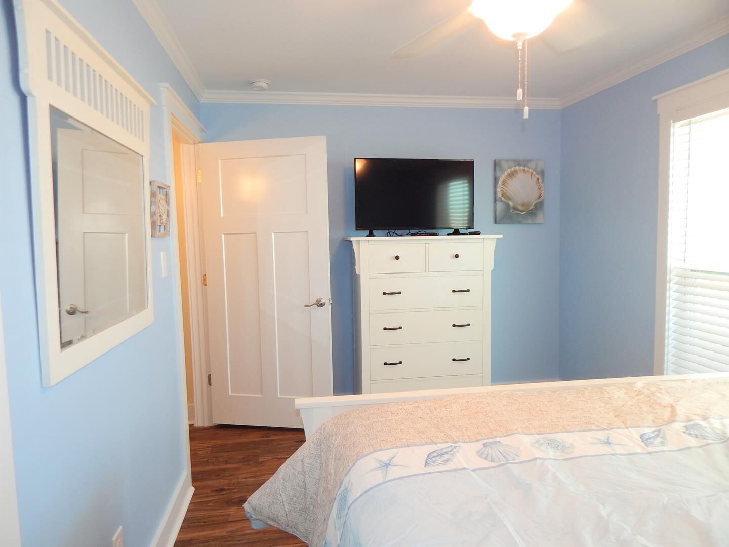 A bedroom with a bed, a dresser, a television, and a door.