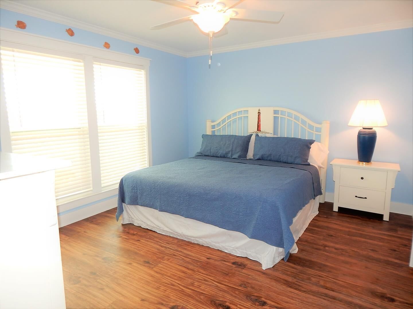 A bedroom with a bed, nightstand, lamp, and a ceiling fan.