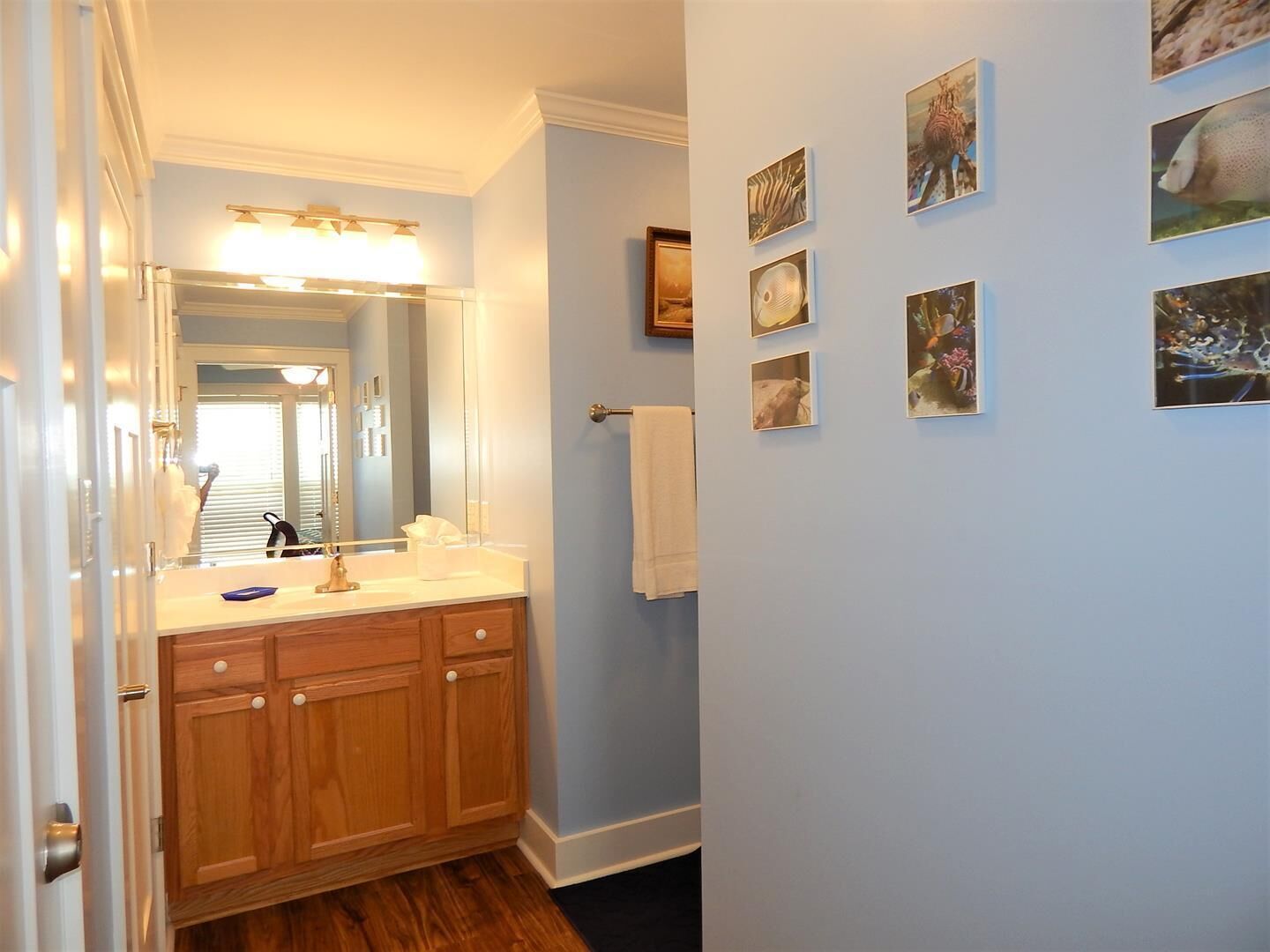 A bathroom with a wooden vanity, a large mirror, and a wall adorned with framed pictures.