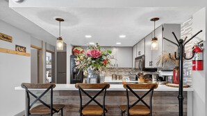 A modern kitchen with a central island, bar stools, and a decorative flower arrangement. - Fireplace | Giant Steps Condo | Ski Out Access (Brian Head)