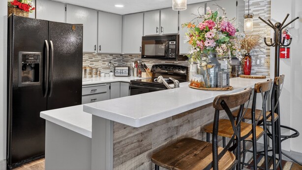 A modern kitchen with a central island, stainless steel appliances, and a decorative vase with flowers. - Fireplace | Giant Steps Condo | Ski Out Access (Brian Head)