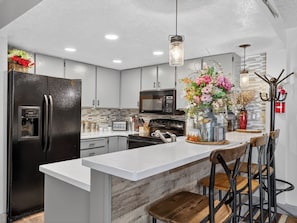 A modern kitchen with a central island, stainless steel appliances, and a decorative vase with flowers. - Giant Steps 12 Rustic Retreat ski in/out 2bd/2bath (Brian Head)