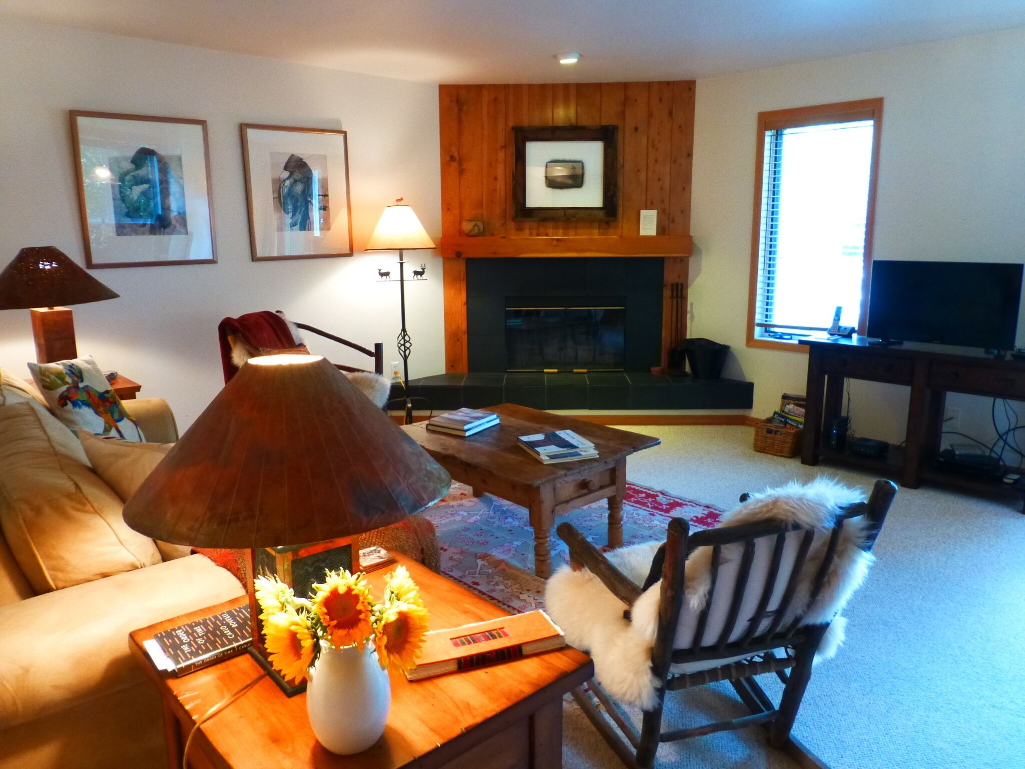 A living room with a sofa, a coffee table with a lamp, a fireplace, and a TV.