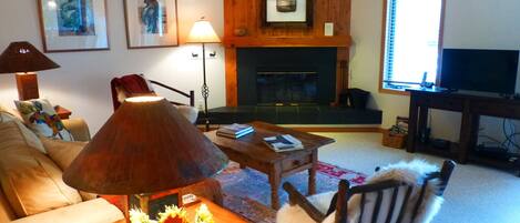 A living room with a sofa, a coffee table with a lamp, a fireplace, and a TV.