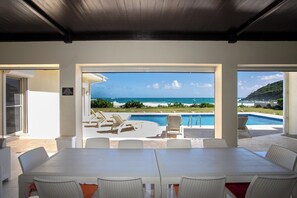 Un comedor con vista a una piscina y al océano.