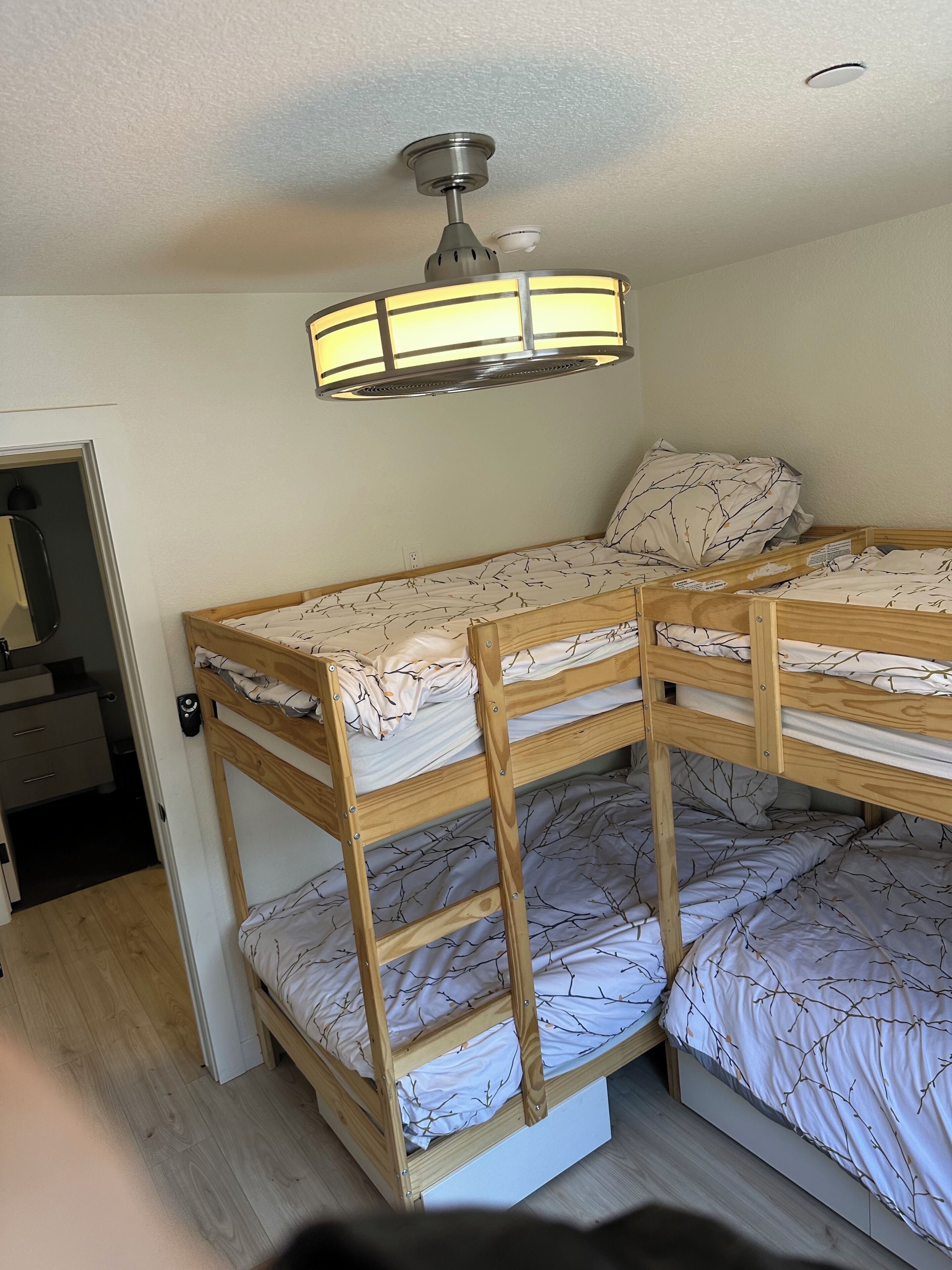 A bunk bed room with a ceiling fan and a light fixture.