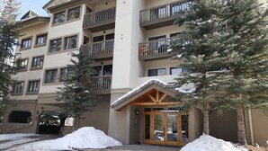 Ein mehrstöckiges Hotel mit Balkonen, einem überdachten Eingang und Schnee auf dem Boden.