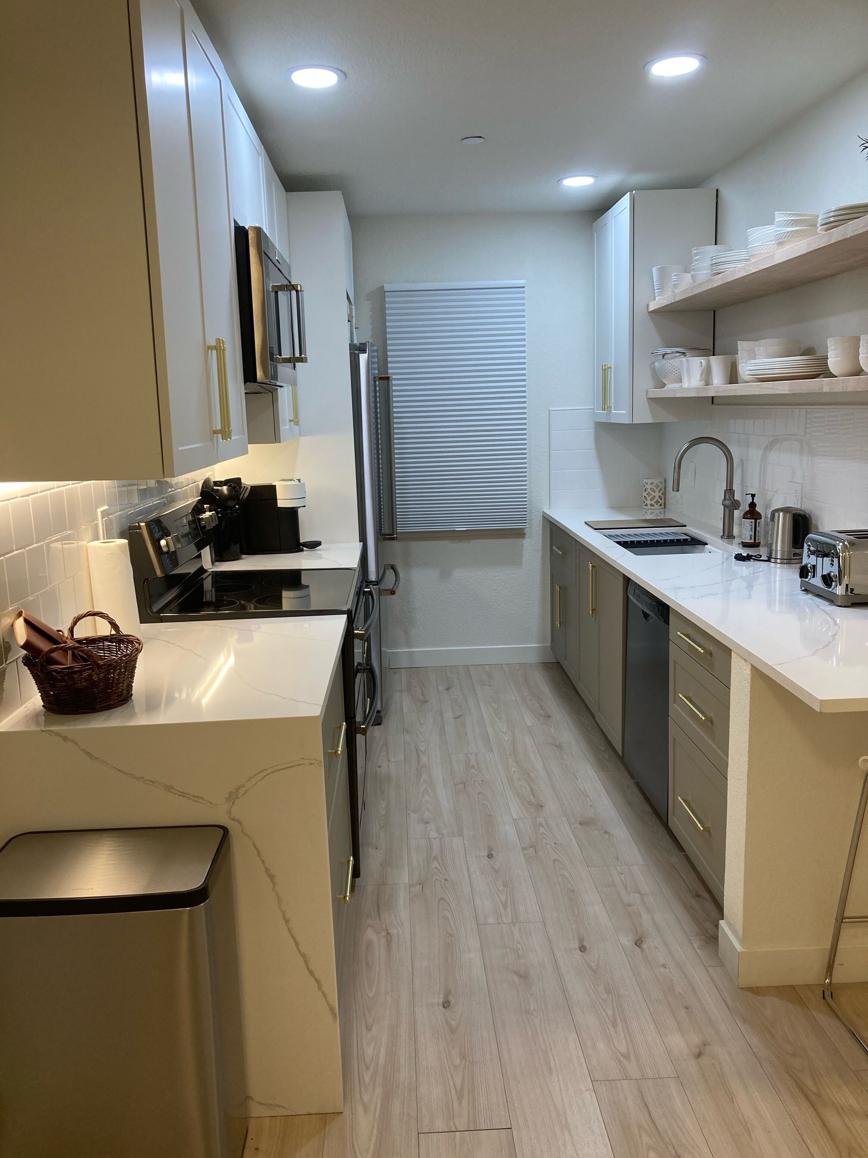 A modern kitchen with white cabinetry, a built-in oven, a coffee machine, and a sink.