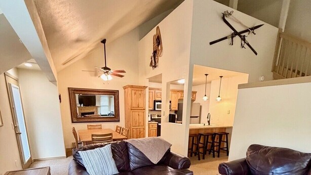 A spacious living room with leather sofas, a coffee table, and a dining area with wooden cabinets and a kitchen in the background. - Hidden Creek Ski Rentals (Park City)