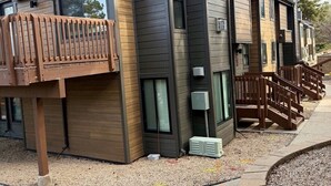 A modern multi-story residential building with a wooden deck, large windows, and a chimney. - Hidden Creek Ski Rentals (Park City)