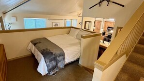 A bedroom with a bed, a desk, and a staircase. - Hidden Creek Ski Rentals (Park City)