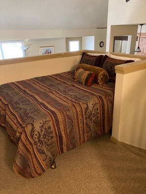 Cozy retreat with a large bed and multiple pillows, featuring a patterned bedspread.