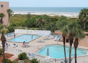 A pool area with two pools, lounge chairs, and a view of the beach. - STBT 117: Seaside Escape: Pool & Beach Access (St. Augustine)