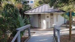 A small, single-story building with a sloped roof, a wooden fence, and a signpost.