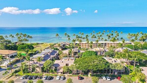 Un resort con varias construcciones, un estacionamiento y vista al océano.