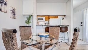 Una cocina compacta con armarios blancos, un microondas y un refrigerador.