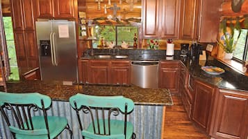 Una cocina con armarios de madera, un refrigerador de acero inoxidable, lavavajillas y encimera de granito.