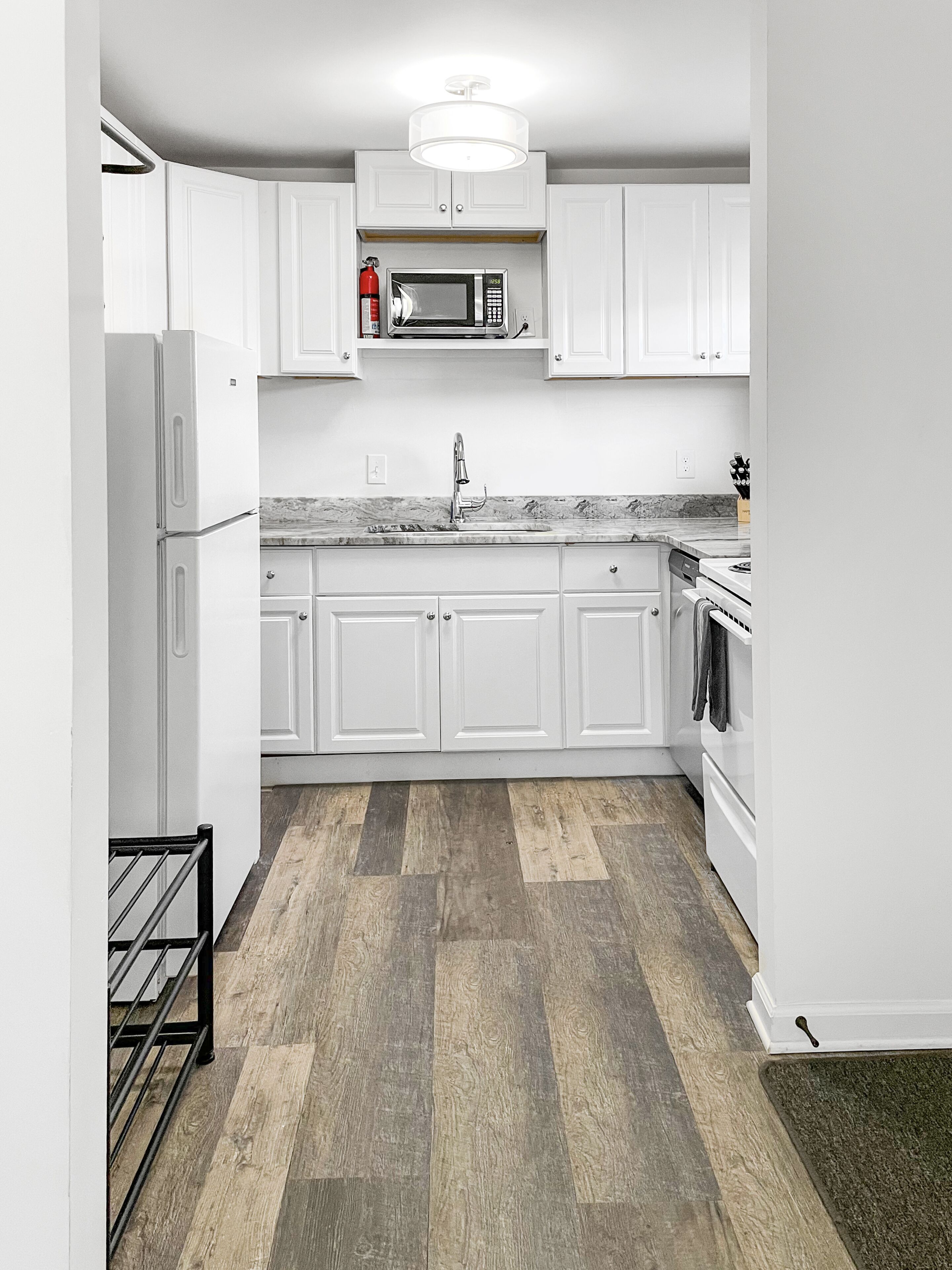 A modern kitchen with white cabinetry, a stainless steel microwave, and a built-in oven.